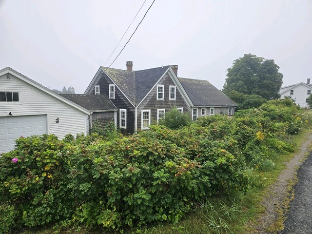 view of front of property with a chimney, a shingled roof, and a garage