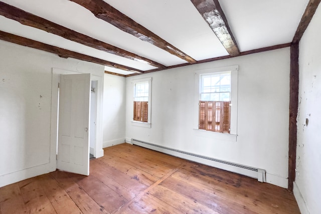 empty room with hardwood / wood-style flooring, beamed ceiling, and a baseboard heating unit