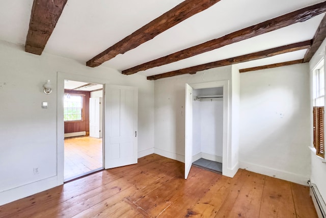 unfurnished bedroom featuring beam ceiling, a closet, light hardwood / wood-style flooring, and a baseboard radiator