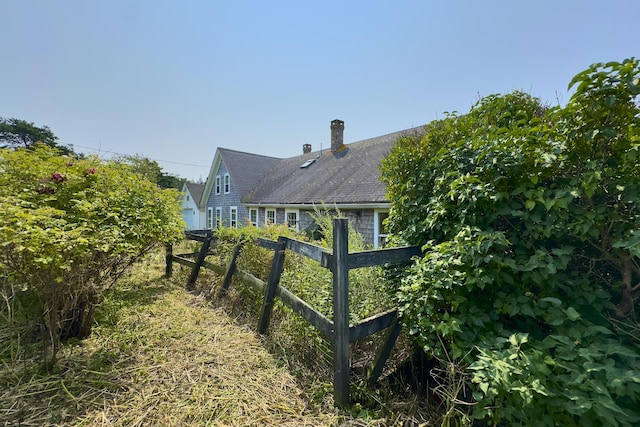 view of side of home with a vegetable garden, fence, and a chimney