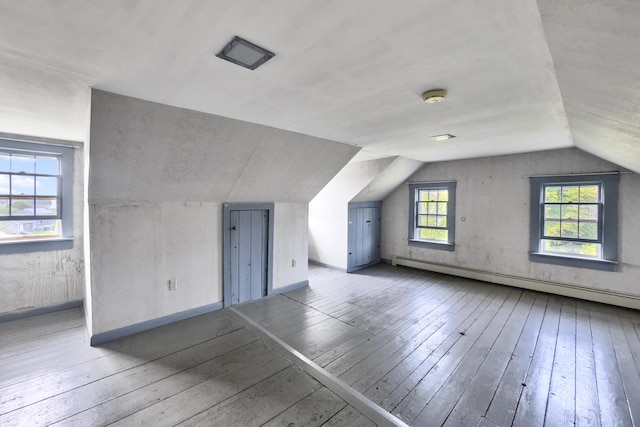 bonus room with baseboards, lofted ceiling, a baseboard heating unit, and wood-type flooring