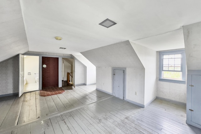 additional living space featuring hardwood / wood-style flooring, baseboards, and vaulted ceiling