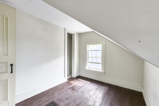 additional living space with baseboards, lofted ceiling, and dark wood-style flooring