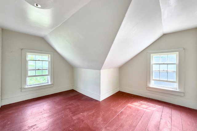 additional living space featuring vaulted ceiling, hardwood / wood-style floors, and a healthy amount of sunlight