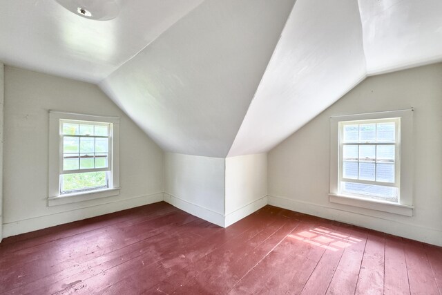 bonus room with baseboards, vaulted ceiling, and dark wood-style flooring