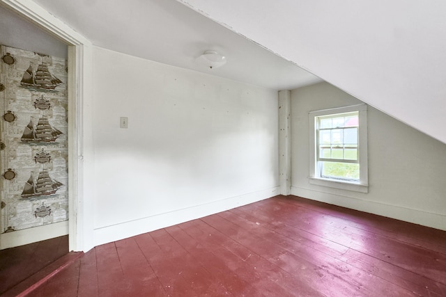 additional living space with baseboards, vaulted ceiling, and dark wood-type flooring