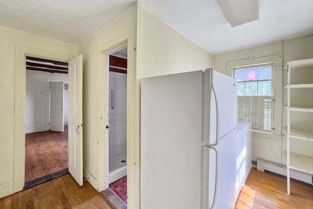 kitchen with a baseboard radiator, hardwood / wood-style flooring, and white refrigerator