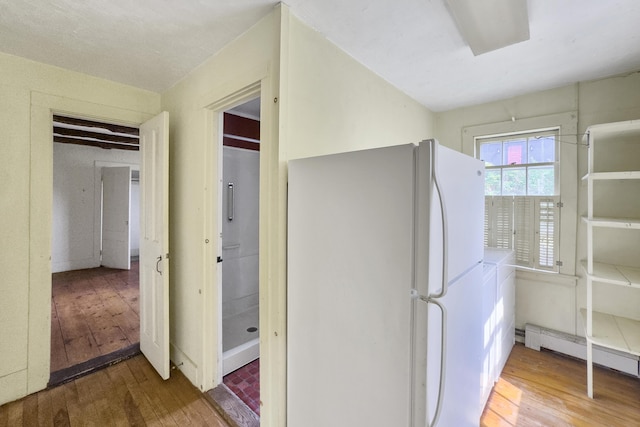kitchen with hardwood / wood-style floors, baseboard heating, and freestanding refrigerator