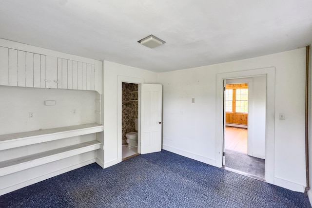 unfurnished bedroom featuring hardwood / wood-style floors, a baseboard radiator, and ensuite bath