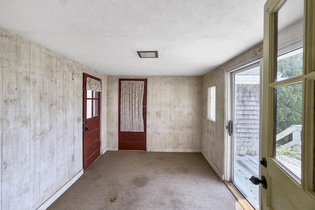 carpeted spare room with wood walls