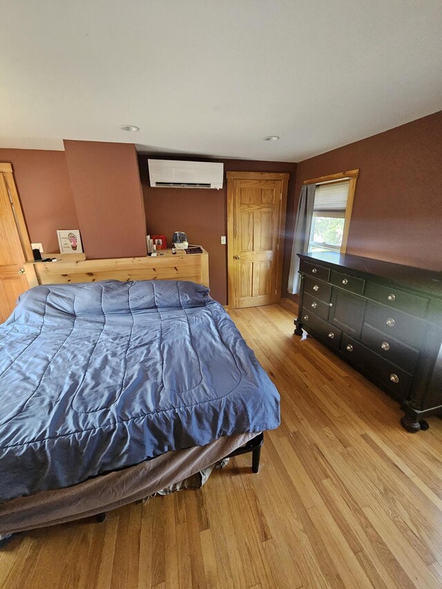 bedroom with wood-type flooring and a wall unit AC