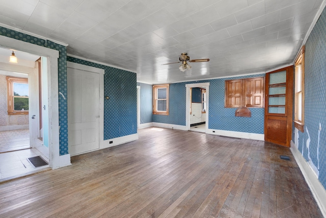 unfurnished living room with hardwood / wood-style flooring, ornamental molding, and ceiling fan