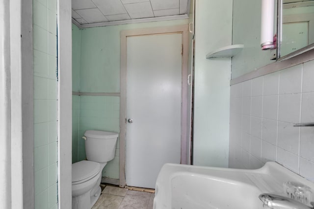 bathroom featuring tile walls and toilet