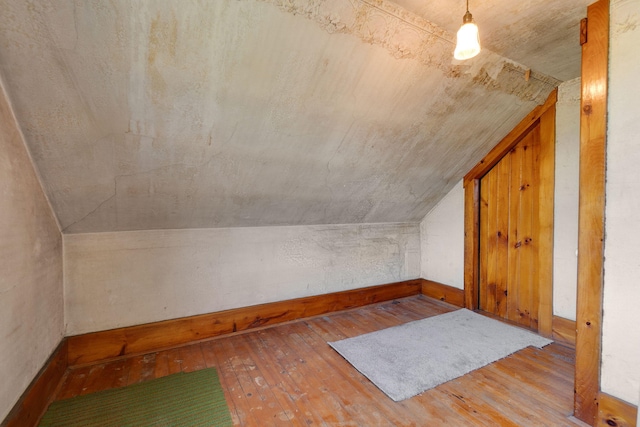 additional living space with vaulted ceiling and light hardwood / wood-style floors