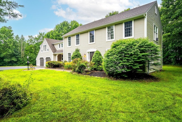 colonial house featuring a garage and a front lawn