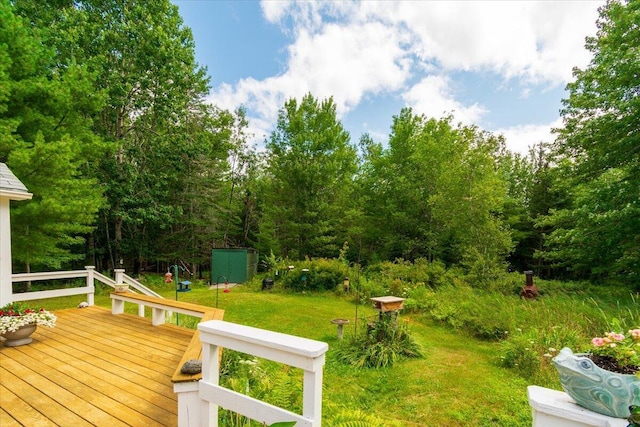 wooden deck featuring a storage unit and a lawn