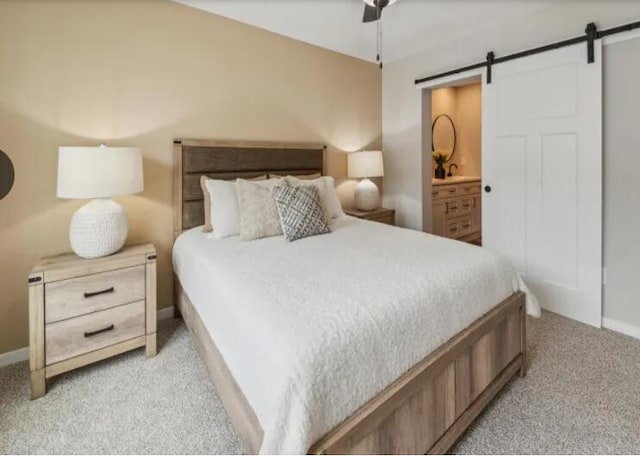 bedroom featuring a barn door, light carpet, connected bathroom, ceiling fan, and baseboards