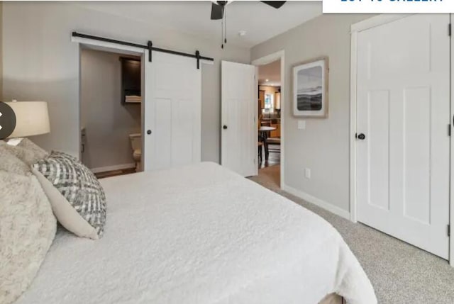 bedroom with a barn door, baseboards, ceiling fan, and carpet flooring