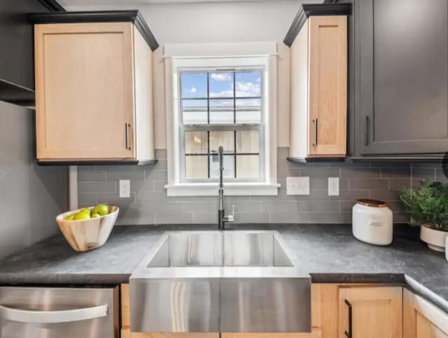 kitchen featuring dark countertops, tasteful backsplash, light brown cabinets, and a sink