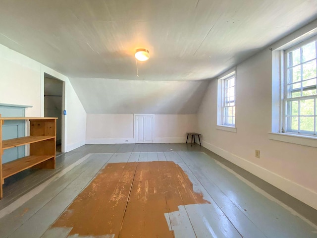 bonus room with a healthy amount of sunlight, wood-type flooring, and baseboards