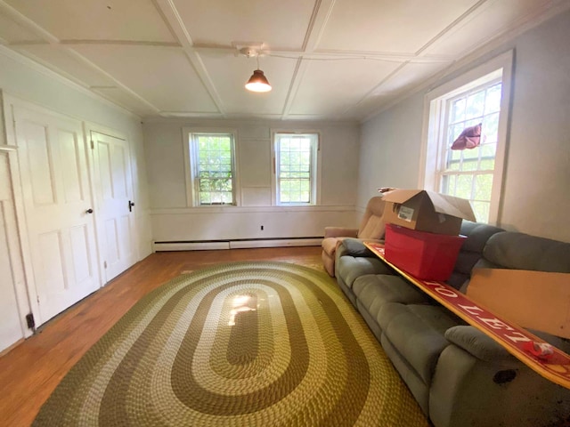 living area with a baseboard heating unit, coffered ceiling, and wood finished floors