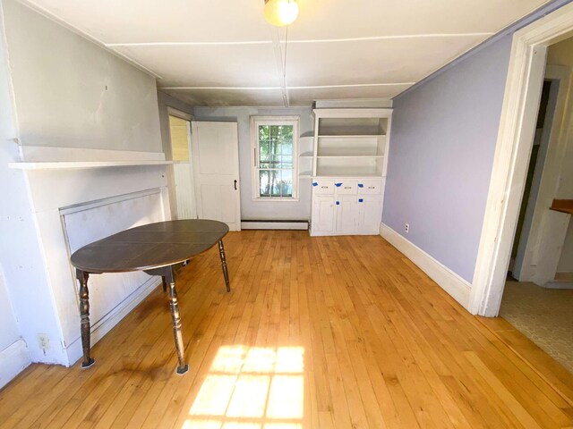 unfurnished dining area featuring light wood-style floors, a baseboard radiator, a fireplace, and baseboards