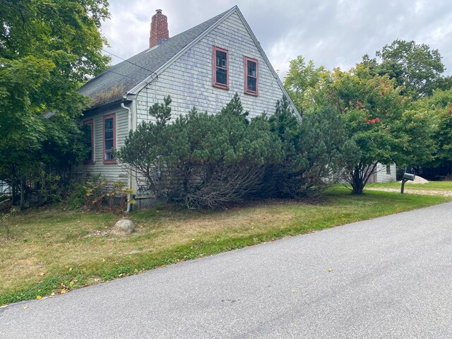 view of side of property featuring a yard and a chimney