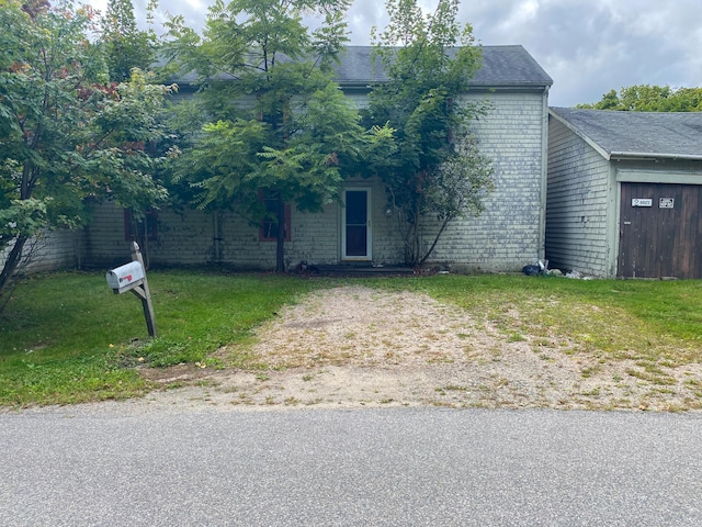 view of property hidden behind natural elements with a front lawn and brick siding