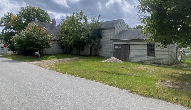 view of front facade featuring a front lawn, a chimney, and brick siding