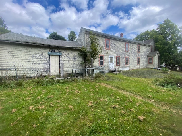 back of property featuring a yard, a chimney, and fence