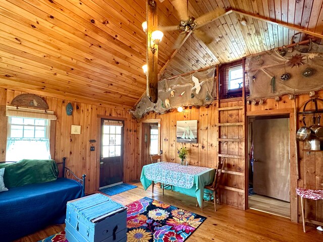 living room with lofted ceiling, wood walls, wood ceiling, and light hardwood / wood-style floors