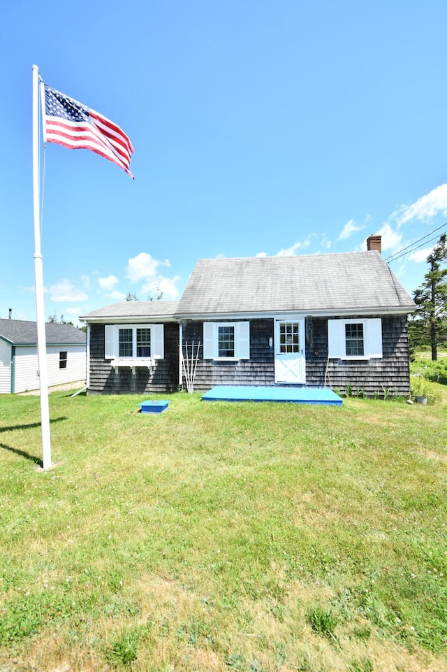 rear view of house featuring a chimney and a yard