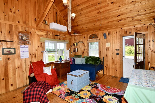 bedroom with an AC wall unit, wooden walls, beam ceiling, and hardwood / wood-style floors