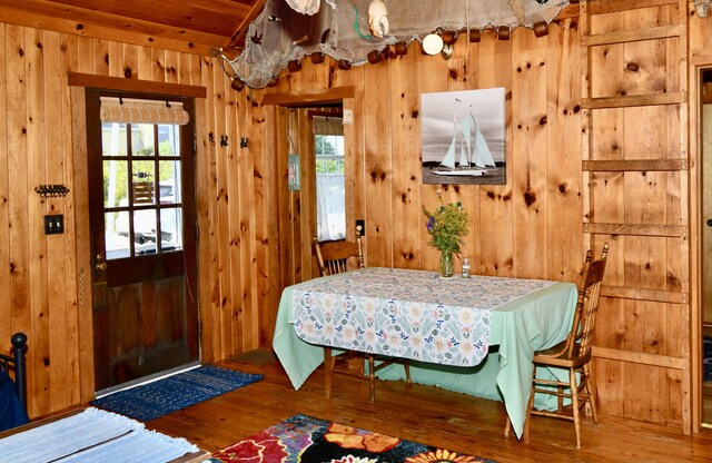 dining room with hardwood / wood-style floors, wood walls, and plenty of natural light