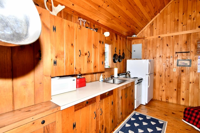 kitchen featuring vaulted ceiling, light hardwood / wood-style floors, wood walls, white appliances, and sink