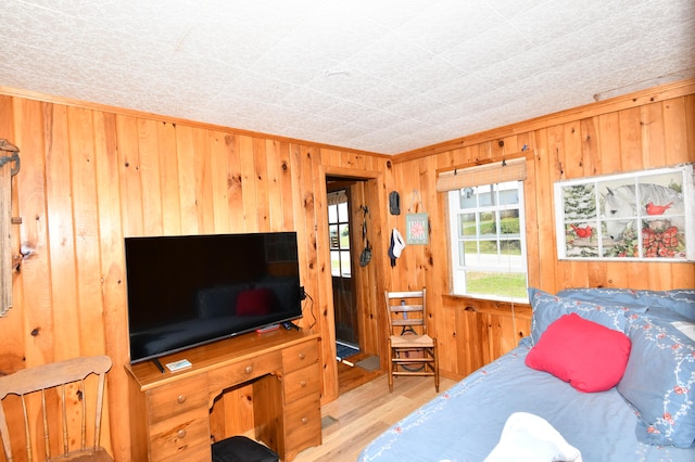 bedroom featuring wood walls, light hardwood / wood-style flooring, and ornamental molding