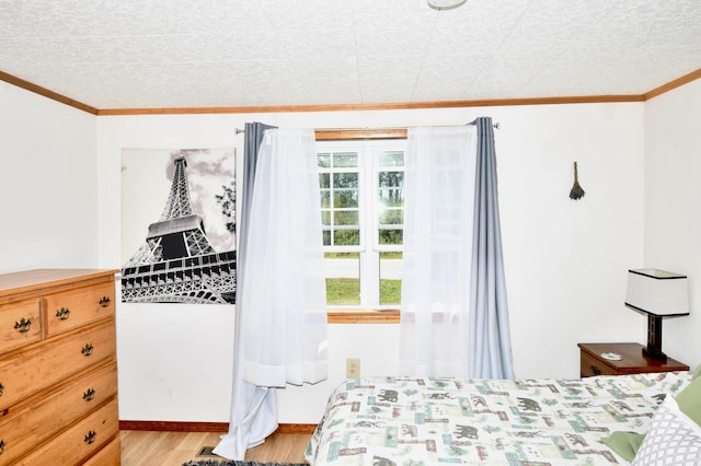 bedroom featuring light wood finished floors, baseboards, and ornamental molding