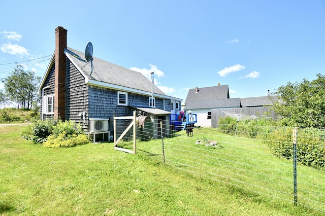 rear view of property featuring ac unit, a chimney, fence, and a lawn