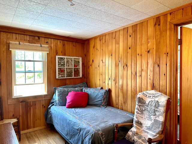 bedroom with wood walls and hardwood / wood-style flooring