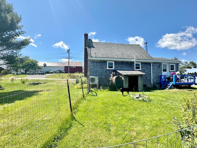 back of house featuring fence, a chimney, and a lawn