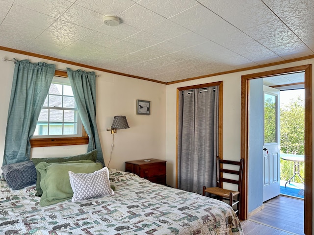 bedroom with multiple windows, hardwood / wood-style floors, and ornamental molding