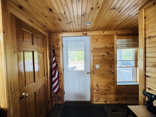 entryway with wood walls, wooden ceiling, and plenty of natural light