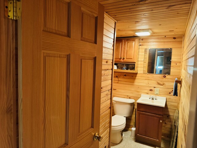 bathroom with wood ceiling, wood walls, toilet, and vanity