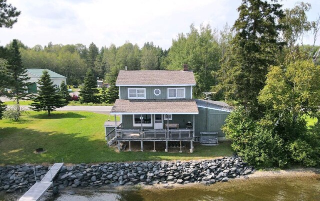 rear view of house with a deck with water view and a yard