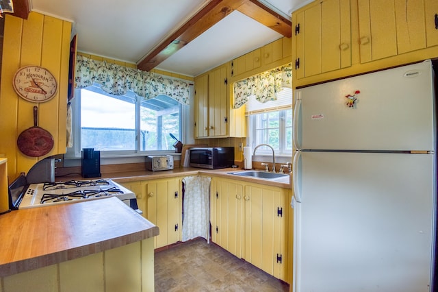 kitchen with white refrigerator, sink, beam ceiling, stove, and light tile patterned floors