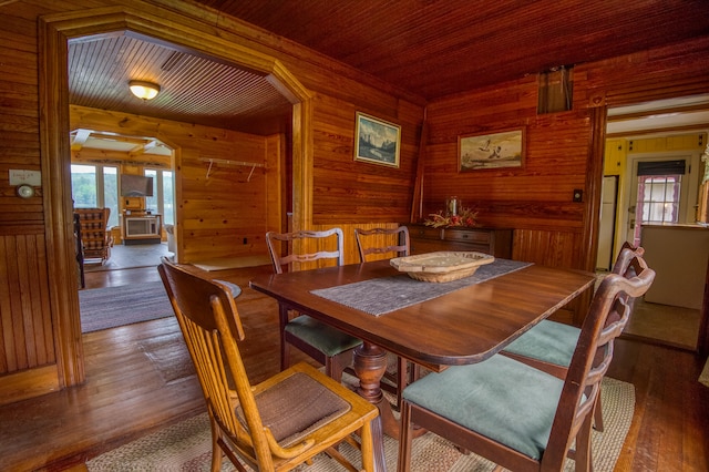 dining room with wood-type flooring, wood ceiling, and wooden walls