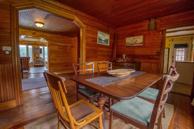 dining space with hardwood / wood-style floors, wood walls, and wooden ceiling