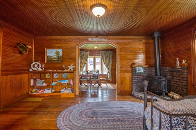 living room featuring a wood stove, hardwood / wood-style flooring, wooden walls, and wood ceiling