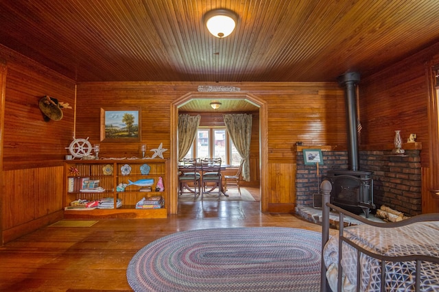 interior space featuring a wood stove, wooden walls, and hardwood / wood-style flooring