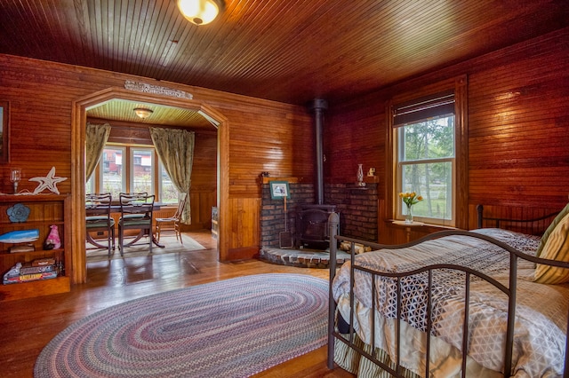 bedroom featuring hardwood / wood-style flooring, a wood stove, and wood walls